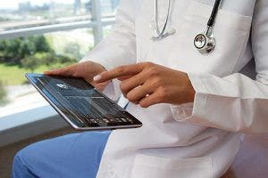 A doctor interacts with an electronic device to digitally communicate with patients.