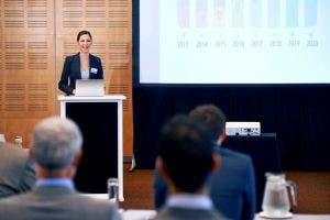 A PR specialist stands at a podium giving a presentation.