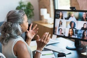 A businessperson gestures during a video call with colleagues.