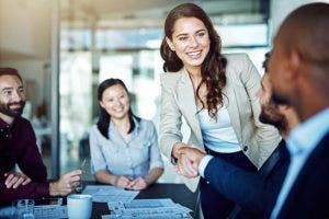 Two co-workers shake hands during a meeting.
